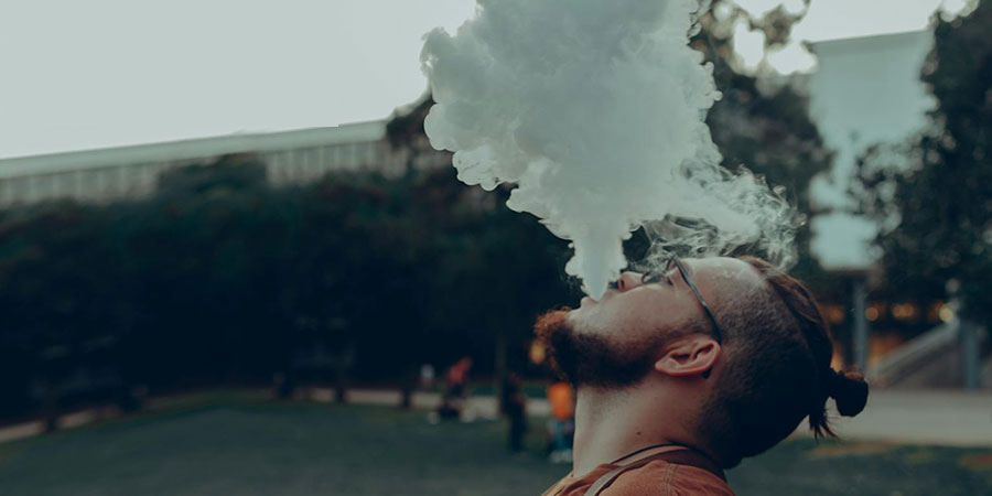 a man vaping and exhaling vapor upward into the air